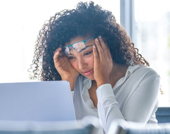 Mulher jovem em frente a um portátil com um ar desconsolado